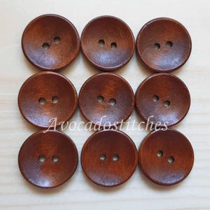 May include: Nine brown wooden buttons with two holes each. The buttons are round and have a slightly raised centre.