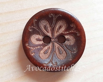 May include: A brown wooden button with a carved floral design. The button has two holes.
