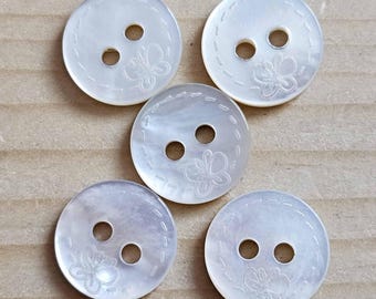 May include: Five round, white, iridescent mother-of-pearl buttons, each featuring two central holes and an engraved butterfly design. A circular dashed line pattern is etched around the perimeter of each button, highlighting the natural sheen.