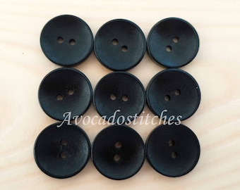 May include: Eight black wooden buttons with two holes each. The buttons are round and have a slightly raised center.