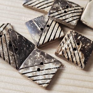 May include: A collection of six brown and white coconut shell buttons with a geometric pattern. The buttons are square shaped and have two holes each.