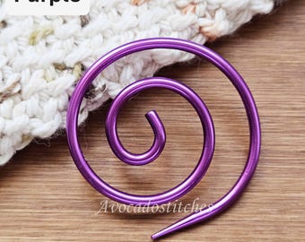 Könnte beinhalten: Ein violetter Maschenmarkierer aus Metall in Spiralform mit glatter, glänzender Oberfläche. Das kreisförmige Drahtdesign weist ein spitz zulaufendes Ende auf, das sich zur Mitte hin krümmt. Der Text 'Purple' ist oben links und 'Avocadostitches' unten zu sehen.