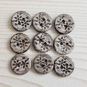 May include: Eight brown coconut shell buttons with a white floral design. The buttons have two holes each.