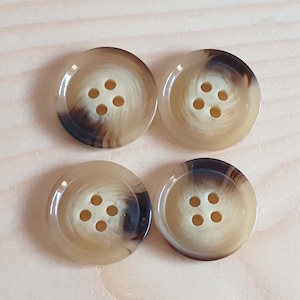 May include: Four round buttons arranged in a square formation. Each button features a smooth, polished surface with a swirling pattern of beige, cream, and dark brown tones. Every button has four centered holes for attachment and a raised outer rim.