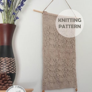 May include: A beige knitted wall hanging with a lace pattern. The hanging has tassels on the bottom and is labeled "Lace Tree - wall hanging" and "Knitting Pattern".