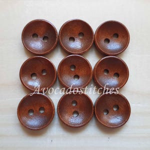 May include: Ten brown wooden buttons with two holes each. The buttons are round and have a slightly raised edge.