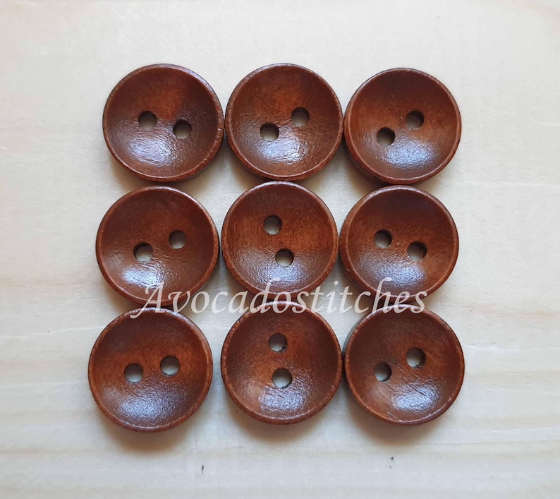 May include: Ten brown wooden buttons with two holes each. The buttons are round and have a slightly raised edge.