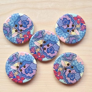 May include: Five round buttons featuring a vibrant floral pattern in shades of blue, purple, pink, and red. Each button has four holes in the centre for attachment. The surface of the buttons displays a detailed illustration of layered flower petals.