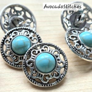 May include: Close-up of several silver-toned buttons with a turquoise stone centre. The buttons have an ornate, openwork design around the stone. The text "AvocadoStitches" is in the top right corner.