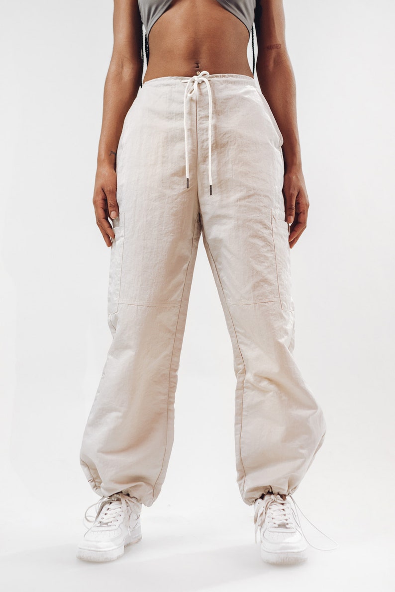 K&ouml;nnte beinhalten: Eine beige Cargohose mit Kordelzugbund und lockerer Passform. Die Hose hat zwei gro&szlig;e Seitentaschen und ist aus leichtem Stoff gefertigt.