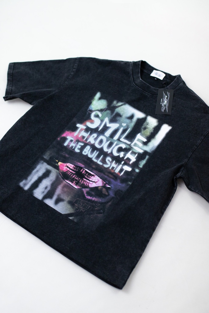 May include: Black short-sleeved t-shirt with a graphic print of a colorful mouth and the text "SMILE THROUGH THE BULLSHIT".