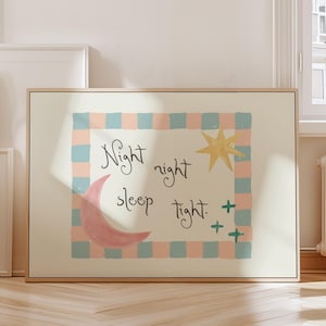 May include: A framed art print with a light beige background. The artwork features a pink crescent moon, a yellow star, and the words "Night night sleep tight" in black script. The design is framed by a blue and pink checkered border.