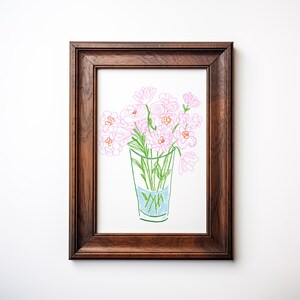 May include: A framed artwork featuring a hand-drawn illustration of pink flowers in a glass vase. The vase has blue water and green stems. The artwork is in a dark brown wooden frame, perfect for home decor.