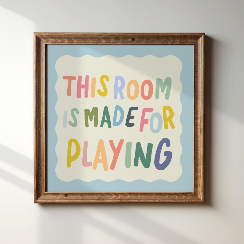 May include: A framed print with a light blue background and a white cloud-shaped border. The text "THIS ROOM IS MADE FOR PLAYING" is written in colorful, playful letters.