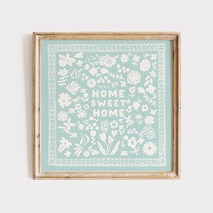 May include: A framed print with a light blue background and white floral designs. The text "Home Sweet Home" is in the center of the print.