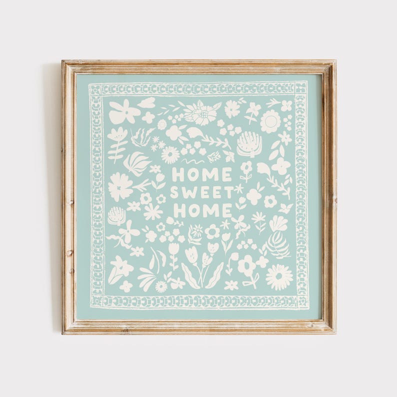 May include: A framed print with a light blue background and white floral designs. The text "Home Sweet Home" is in the center of the print.