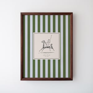 May include: A framed print with a green and white striped background. The print features a black and white illustration of a person riding a horse, with the text "Polo Club Est. 1918" below the image.