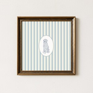 May include: Framed artwork featuring a seated dog illustration within an oval frame. The dog is depicted in a detailed, sketched style. The background has vertical stripes in light blue and cream colors. The frame is a dark brown color.