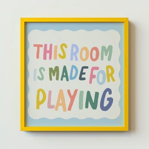 May include: A yellow framed print with a blue background and white clouds. The text "This room is made for playing" is written in colorful letters.