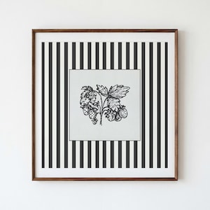 May include: A square framed wall art piece featuring a central light gray panel with a black ink illustration of a strawberry plant. The surrounding border consists of vertical black and white stripes, all enclosed in a dark brown wooden frame.