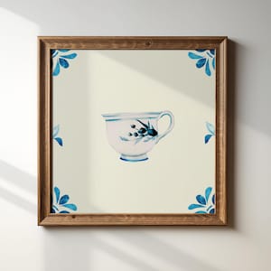 May include: A framed print showing a watercolour illustration of a teacup with blue floral details. The teacup is on a cream background, with blue floral corner designs. The frame is made of wood.