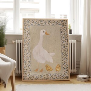 Peut inclure: Une illustration encadr&eacute;e d'une oie blanche avec deux oisons jaunes. Le cadre a un motif floral avec des fleurs bleues et vertes.