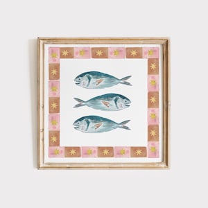 May include: Watercolor print of three blue fish on a white background, framed with a gold-colored border. The frame includes a decorative border of pink and brown squares with gold star accents. The artwork is a decorative piece.