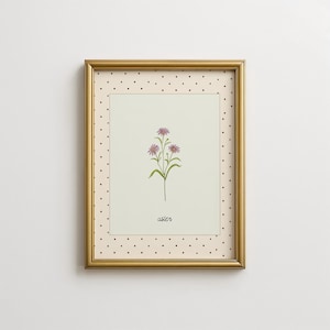 Może przedstawiać: Oprawiony wydruk z botaniczną ilustracją fioletowych kwiatów astrów z zielonymi łodygami i liśćmi. Wydruk ma kremowe tło z kropkowaną obwódką i złotą ramą. Słowo "aster" jest napisane poniżej.