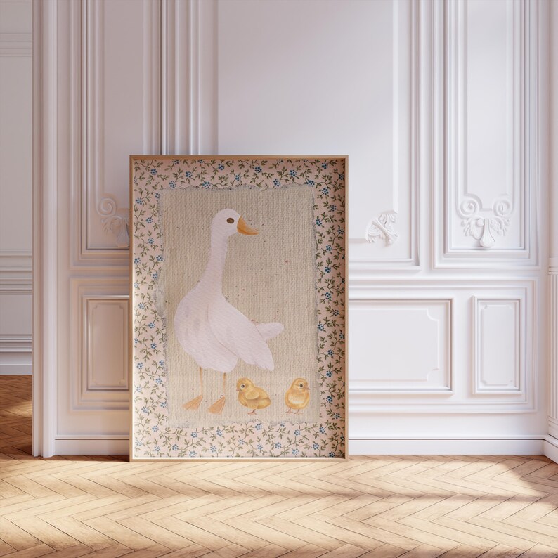 Peut inclure: Une illustration encadr&eacute;e d'une oie blanche avec trois poussins jaunes. L'illustration est entour&eacute;e d'une bordure florale avec des fleurs bleues et blanches.