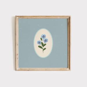 May include: A framed print of a blue flower with a white and blue border on a light blue background.