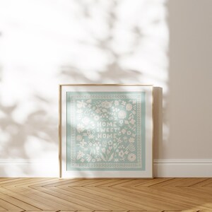 May include: A framed print with a light blue background and white floral design. The text "Home Sweet Home" is centered in the design.