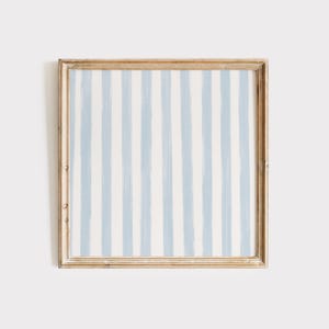 May include: A framed artwork with a blue and white striped pattern. The frame is a light wood color.