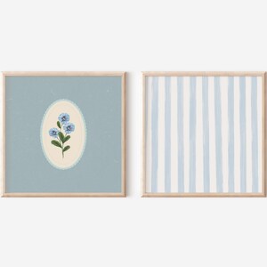 May include: Two framed prints, one with a blue flower illustration in a light blue oval on a light blue background, and the other with a light blue and white striped pattern.