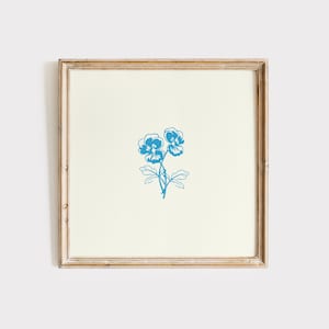 May include: A framed print of a blue floral illustration featuring two pansies with stems and leaves.