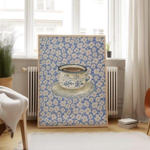 May include: A framed print of a blue and white teacup with a saucer on a blue background with a white floral pattern.