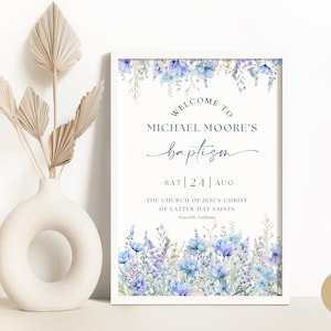 May include: A white sign with blue floral accents announcing a baptism for Michael Moore on Saturday, August 24th at The Church of Jesus Christ of Latter-day Saints in Graniteville, California.