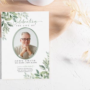 May include: A white memorial card with green foliage border. The card features a photo of a man, the text "Celebrating the Life of John Smith", and the dates "Aug. 30, 1975 - Sept. 29, 20XX". The card also includes information about a memorial service to be held at Eternal Memory Hall on Sept. 10, 20XX at 2:00PM in Serenity Springs, CA.