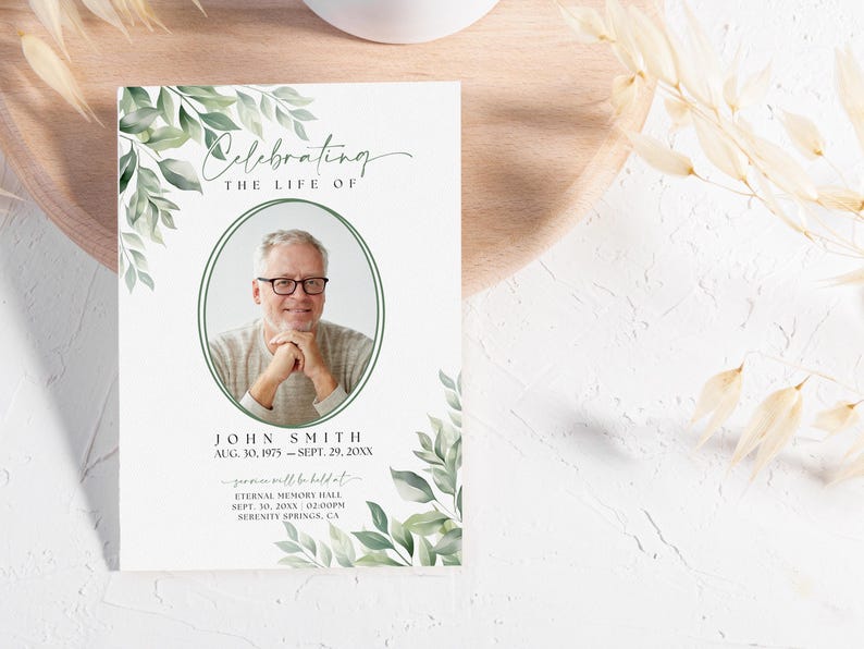 May include: A white memorial card with green foliage border. The card features a photo of a man, the text "Celebrating the Life of John Smith", and the dates "Aug. 30, 1975 - Sept. 29, 20XX". The card also includes information about a memorial service to be held at Eternal Memory Hall on Sept. 10, 20XX at 2:00PM in Serenity Springs, CA.