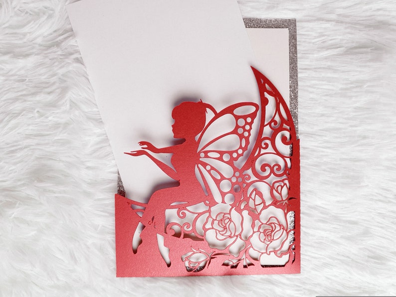 May include: Red laser cut invitation with a fairy sitting on a rose with butterfly wings. The invitation has a silver glitter border.