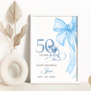 May include: A white printable sign with a blue bow, a martini glass, and the text "50 Years Loved", "Happy Birthday Jane", and "Dec. 30, 20XX".