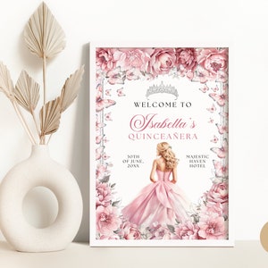 May include: A white framed poster with a pink floral border and butterflies. The text reads "Welcome to Isabella's Quincea&ntilde;era" with the date "10th of June, 20XX" and the location "Majestic Haven Hotel".
