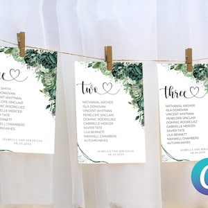 May include: Three white cards with green floral designs and black text. The cards are labeled "one", "two", and "three" and list names for a wedding reception seating chart.