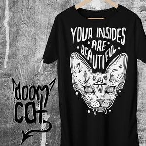 May include: Black t-shirt with a white graphic of a sphinx cat with a pentagram on its forehead and the text "YOUR INSIDES ARE BEAUTIFUL".