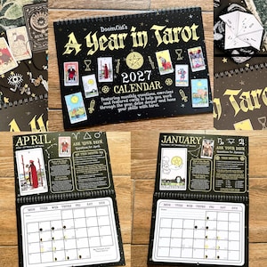 May include: A 2027 spiral-bound wall calendar titled DoomCat's A Year in Tarot with a black cover featuring gold text and tarot card illustrations. The interior pages display monthly grids, tarot card imagery, and instructional text.
