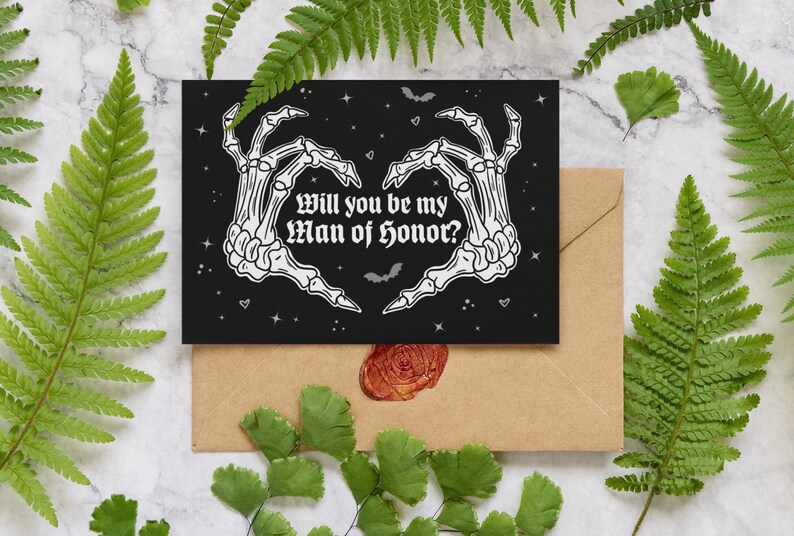 May include: A black card with a white skeleton hand design forming a heart shape. The text reads "Will you be my Man of Honor?" with a black background and white stars.