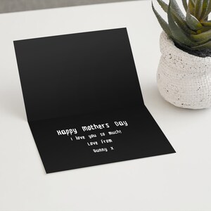 以下が含まれることがあります： 「Happy Mother's Day I love you so much! Love from Bunny x」と書かれた白いテキストの黒いカード