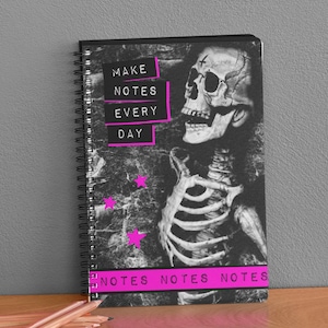 May include: A black and white spiral notebook with a skeleton graphic and the text "MAKE NOTES EVERY DAY" in pink. The notebook also has the text "NOTES NOTES NOTES" in pink at the bottom.