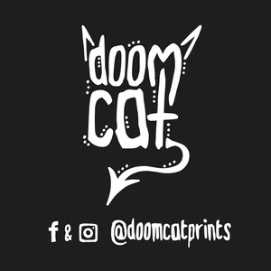 May include: A black graphic with the words "doom cat" in white, stylized with devil horns and a tail. Below the text are social media icons and the handle @doomcatprints.