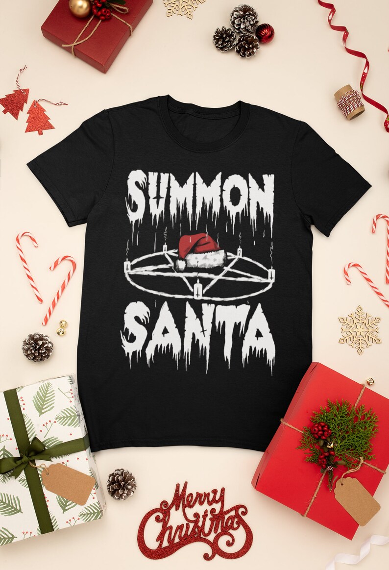 May include: Black t-shirt with the text "SUMMON SANTA" in a dripping font, featuring a pentagram with a Santa hat in the center. The shirt is surrounded by Christmas decorations, including wrapped gifts, candy canes, and pine cones.