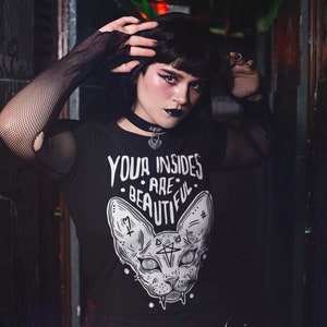 May include: A black t-shirt with a white graphic of a cat with the text "Your insides are beautiful." The cat has large eyes and a pentagram on its forehead.